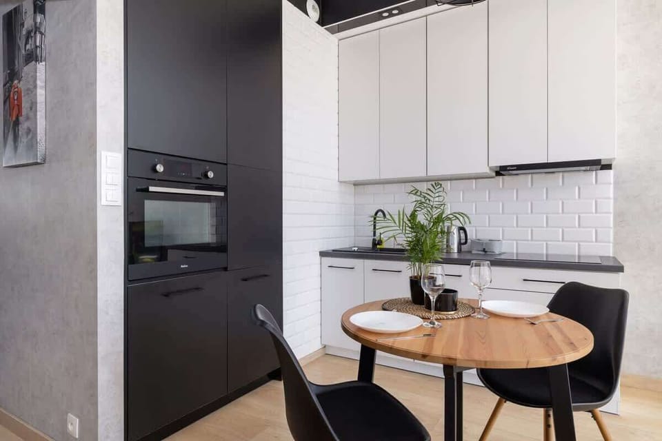 A functional and stylish kitchen area featuring a white subway tile backsplash, ample storage, and integrated appliances.

