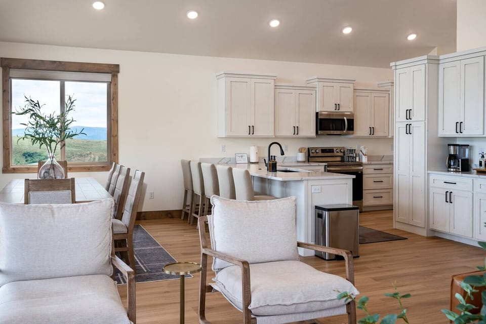 The gourmet kitchen features an island with seating for four and is equipped with stainless steel appliances, including a microwave, gas stove, and spacious refrigerator.