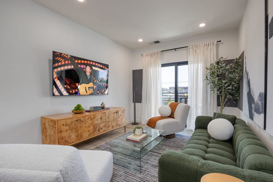 Cozy modern living room featuring a Smart TV, Patio access with city views and designer decor with plush furnishings.