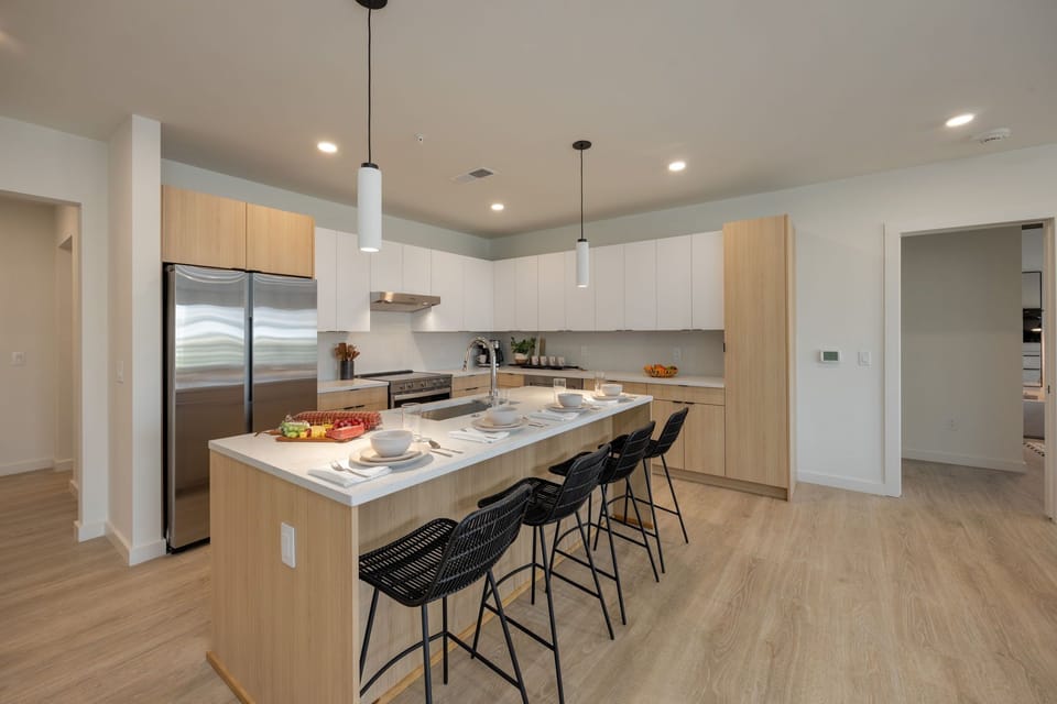 Fully equipped modern kitchen stocked with culinary essentials featuring stainless steel appliances with island bar seating.