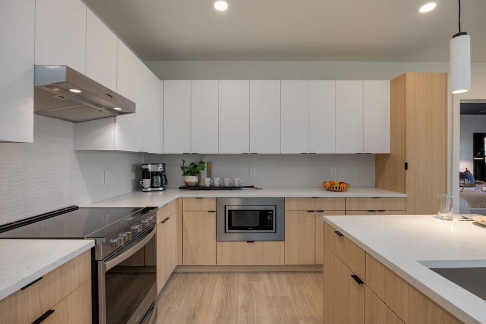Fully equipped modern kitchen stocked with culinary essentials featuring stainless steel appliances with island bar seating.