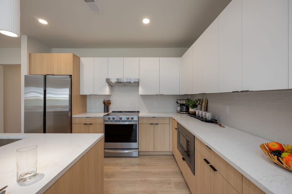 Fully equipped modern kitchen stocked with culinary essentials featuring stainless steel appliances with island bar seating.