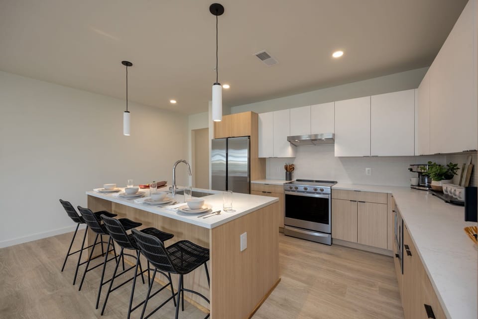 Fully equipped modern kitchen stocked with culinary essentials featuring stainless steel appliances with island bar seating.