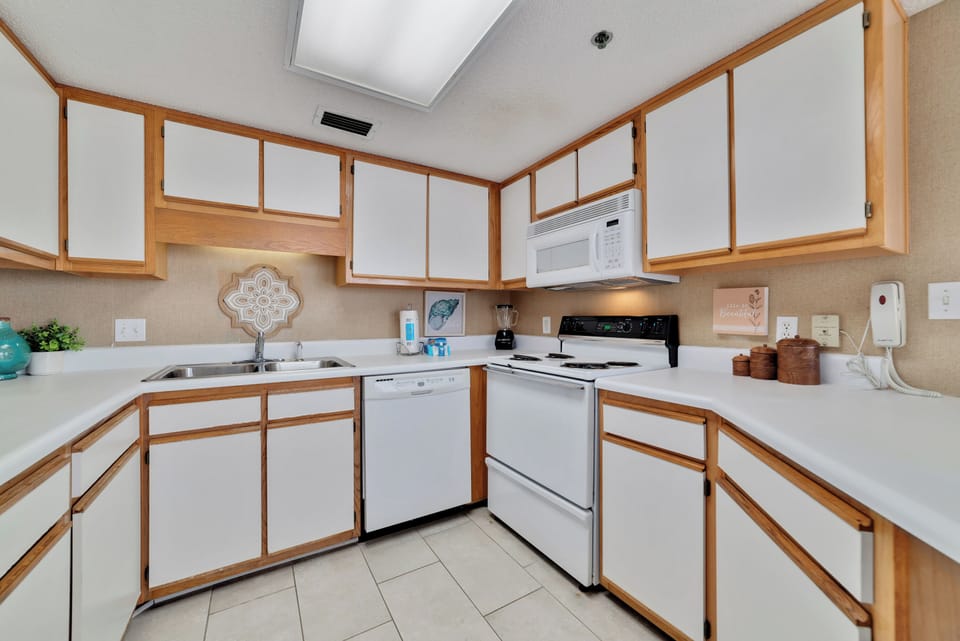 Designed for both functionality and style, this bright kitchen boasts crisp white cabinetry and an open layout that seamlessly connects to the dining area and those stunning panoramic Gulf views. Perfect for entertaining or a quiet morning coffee.