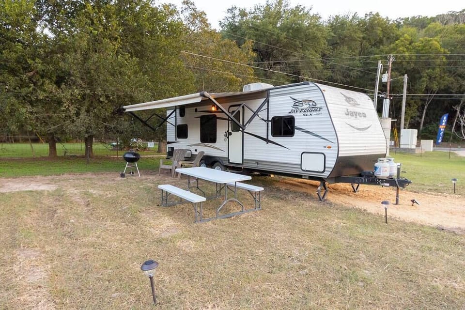 Exterior of RV w/ picnic table, chairs and grill. Not pictured is the fire pit.