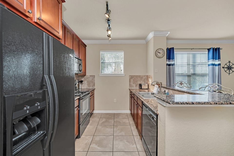 Sleek kitchen with black appliances, tile floors, and large windows for natural light.