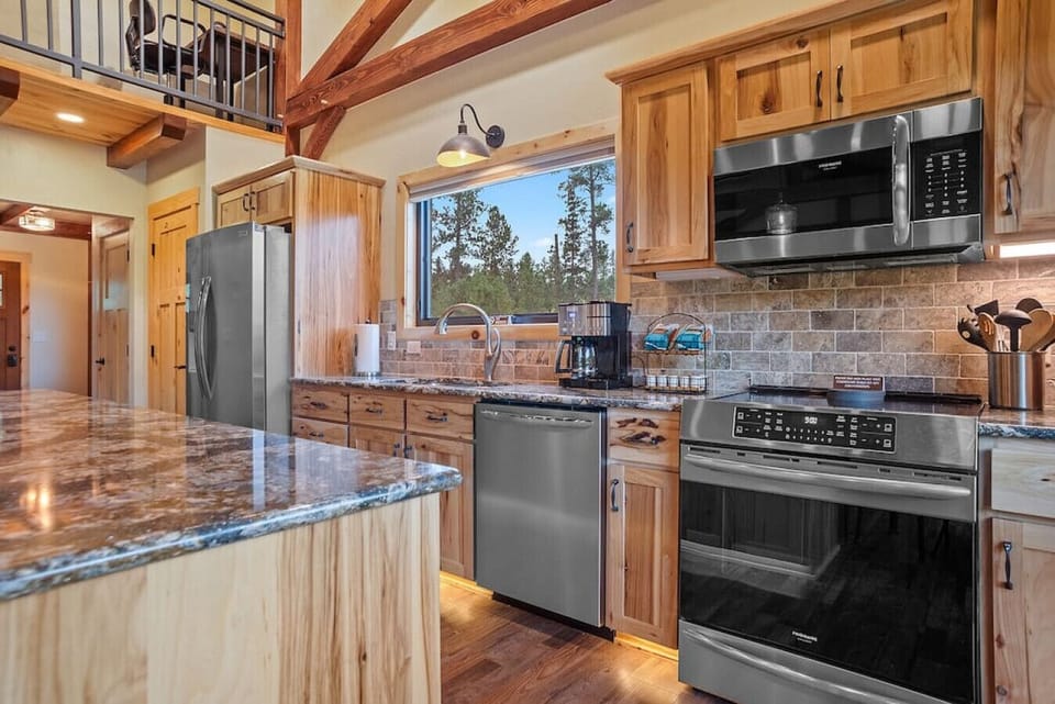 A fully-equipped kitchen awaits, complete with a sleek refrigerator, convenient microwave oven, modern stove, efficient dishwasher, a coffee-maker, and meticulously organized cabinets house an array of kitchenware,