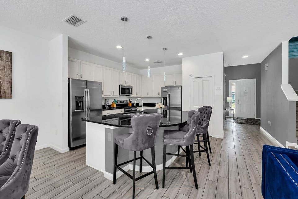 Modern kitchen with a central island, black countertops, and white cabinetry, viewed from the living room angle.