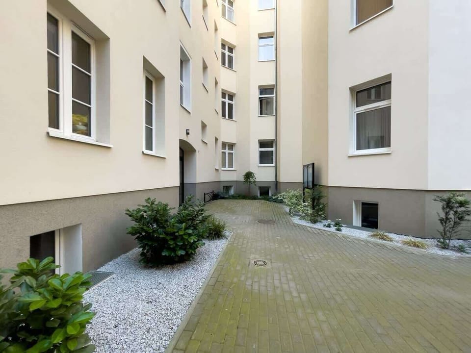 Peaceful courtyard with greenery and paved walkways, offering a serene outdoor area for residents.

