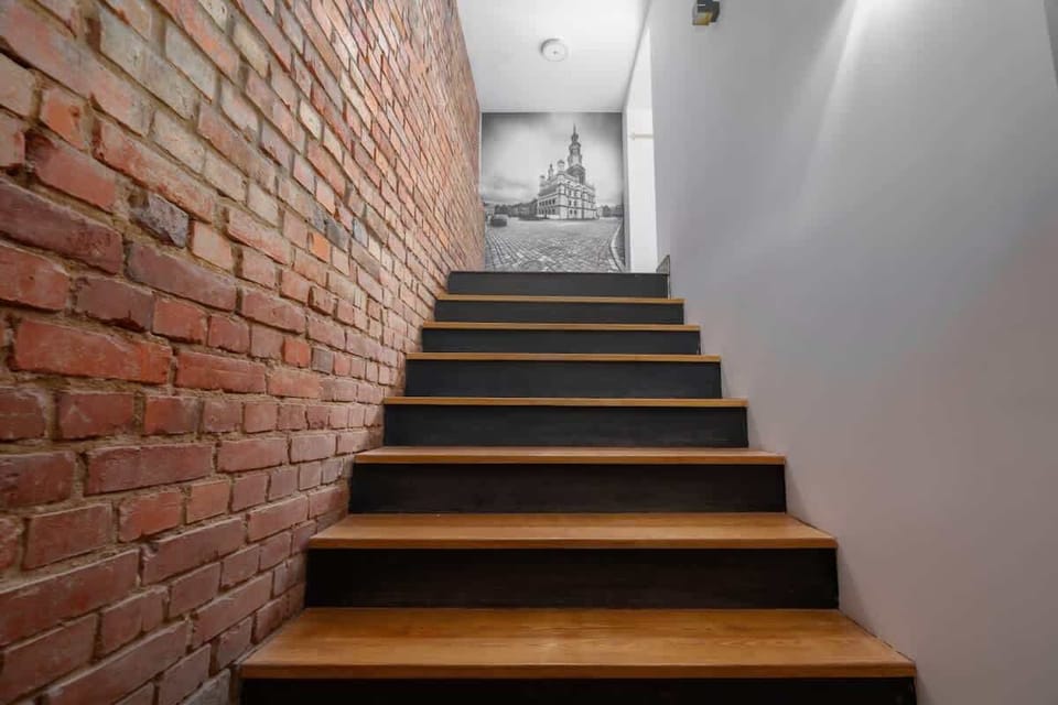 Wooden staircase set against brick walls, blending modern and rustic styles harmoniously.

