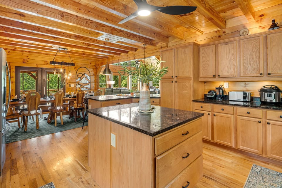 Gather in the heart of the cabin—our chef’s kitchen with granite island, stainless appliances, and a view into the warm dining space.