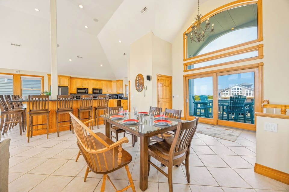 Picture yourself gathering with loved ones at the dining table, where high ceilings and sunlight create an airy, welcoming atmosphere. The open kitchen invites meal prep together, and those glass doors lead to your private deck—perfect for morning coffee o