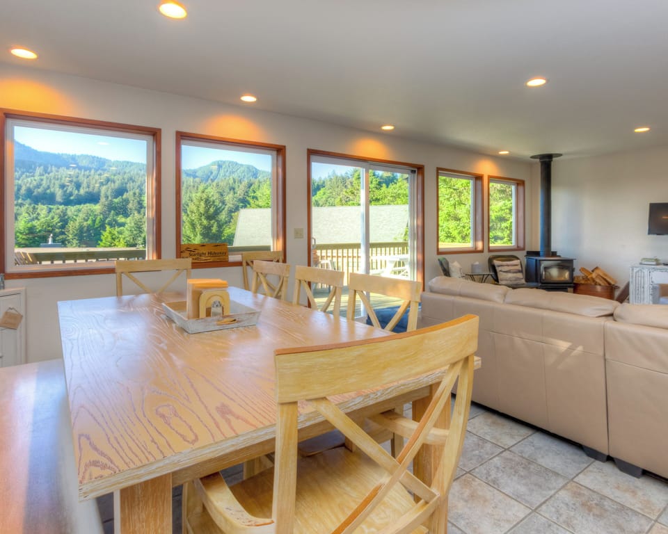 Dining/ Living room with TV, wood fireplace and access to deck with mountain view.