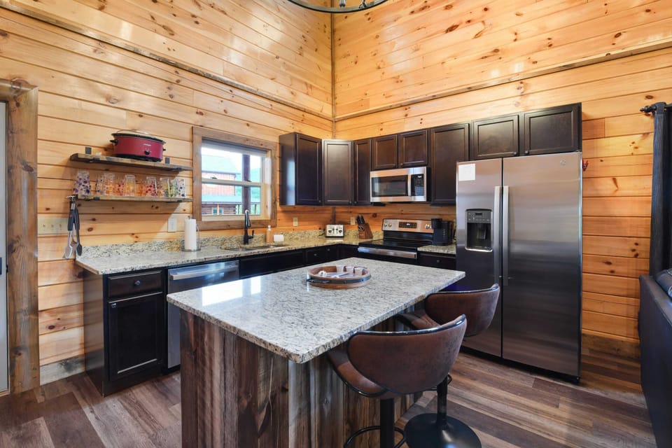 Modern kitchen with granite countertops and stainless steel appliances in a rustic cabin setting