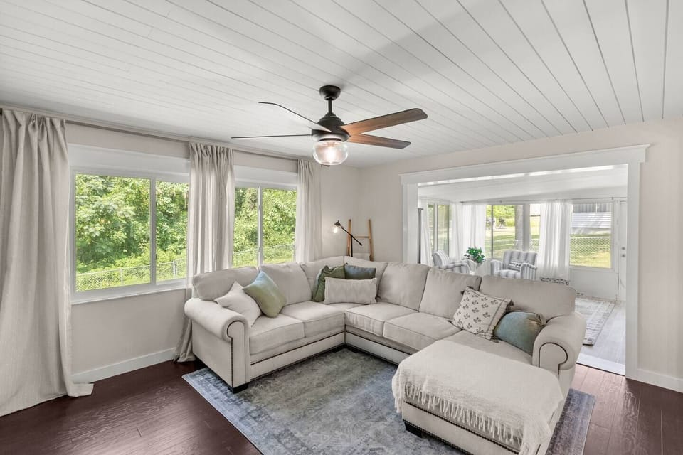 Bright Living Room – Spacious sectional, ceiling fan, and large windows with lush views.