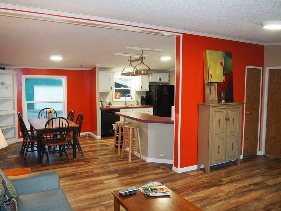 A constructive photo from near the front door that shows the living room, dining room, entrance to the kitchen, a closet door (door on the left), and the door to the master bedroom (door on the right).