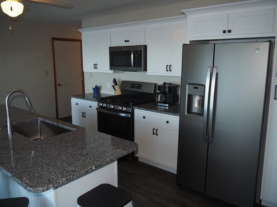 KITCHEN:  Newly remodeled and features a gas stove and stovetop, refrigerator, microwave oven, dishwasher, Keurig coffee maker, toaster, island with sink, barstools, lots of counter space and cabinets, and a good supply of cooking & dining utensils.