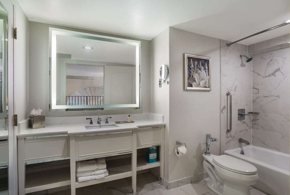 Refresh in a sleek bath with bright mirror and marble shower.