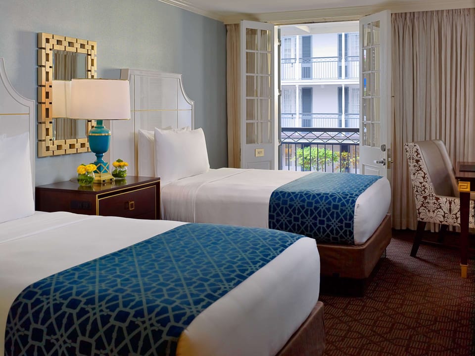 Wake up together in twin beds beside bright balcony doors.