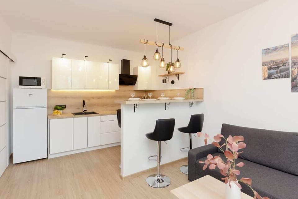 A well-lit dining area with a wooden table, bar stools, and hanging pendant lights for a contemporary feel.
