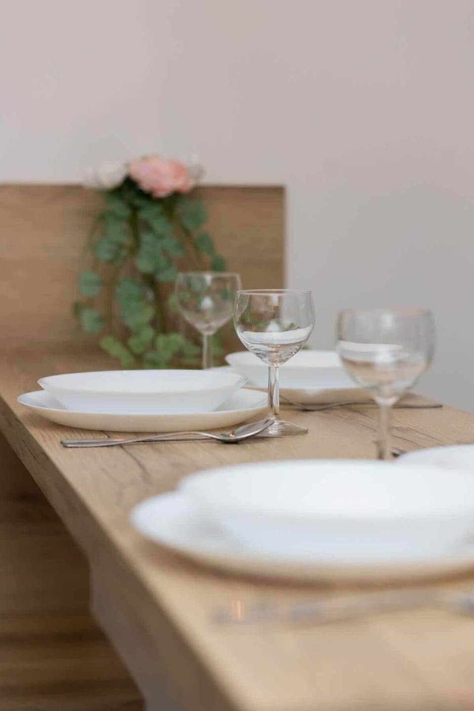 A close-up of a dining setup with plates, glasses, and green floral decor for an inviting atmosphere.
