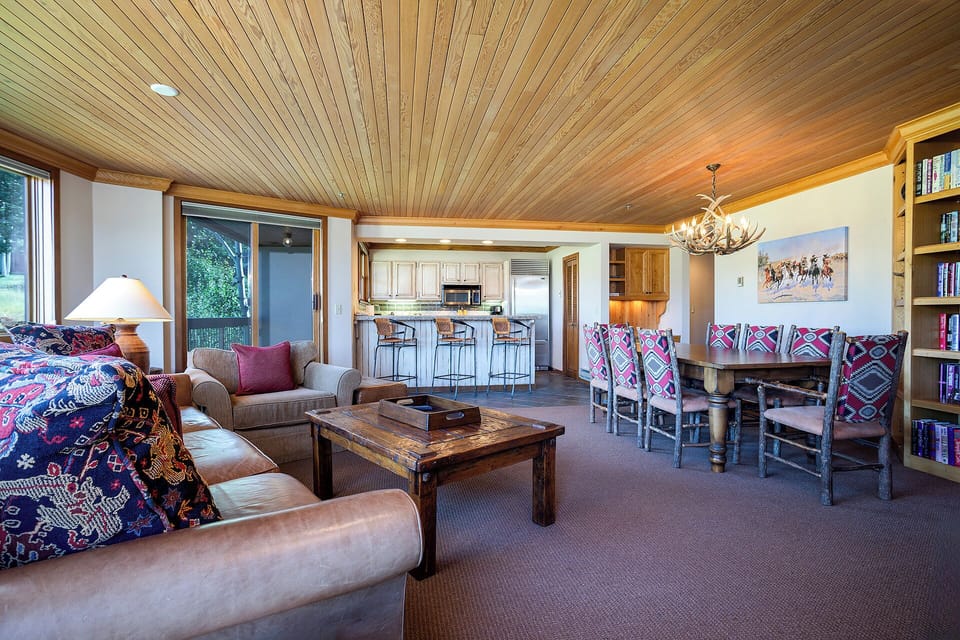 Unwind in this spacious open-plan living area featuring rustic wood ceilings, cozy seating, and a fully equipped kitchen for memorable mountain getaways.