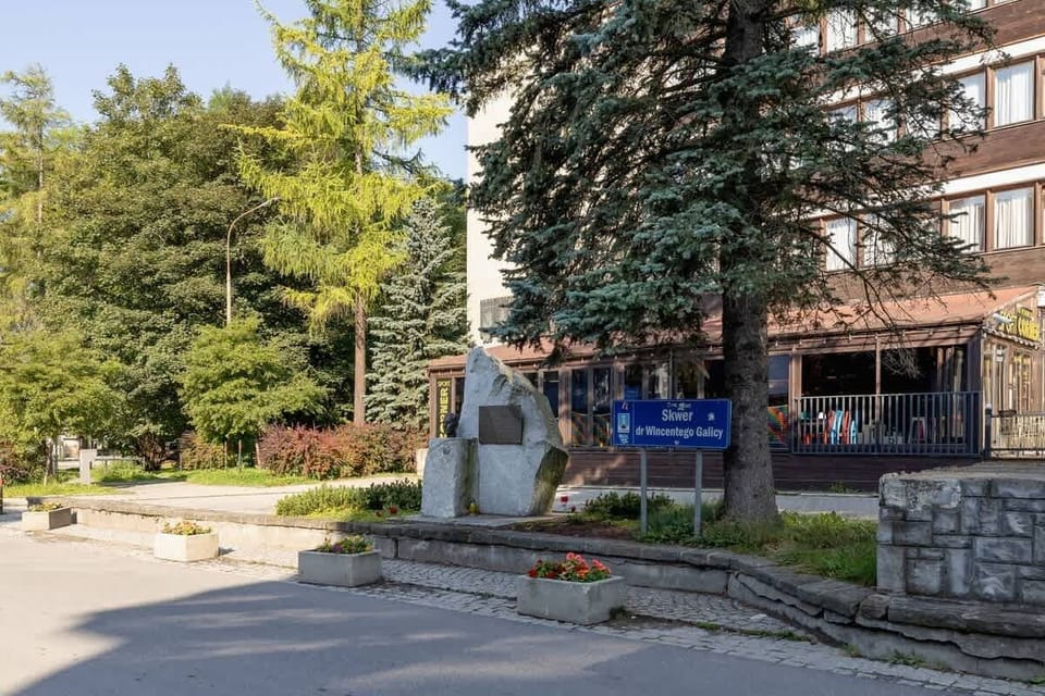A street view showcasing a welcoming entrance to a nearby attraction or building surrounded by greenery.
