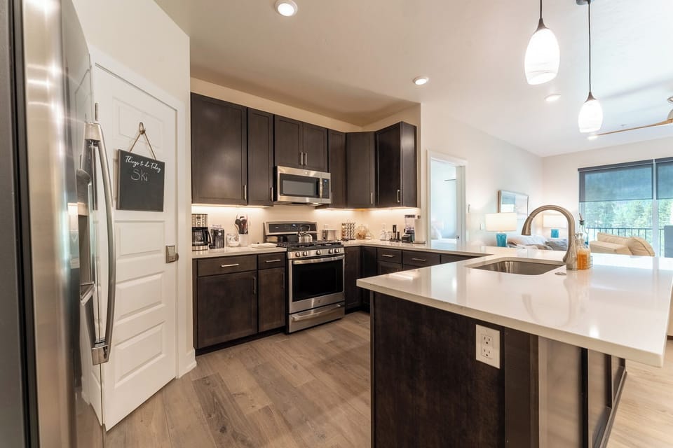 Step into your gourmet kitchen featuring sleek dark cabinets, quartz countertops, and stainless steel appliances perfect for cooking memorable meals.