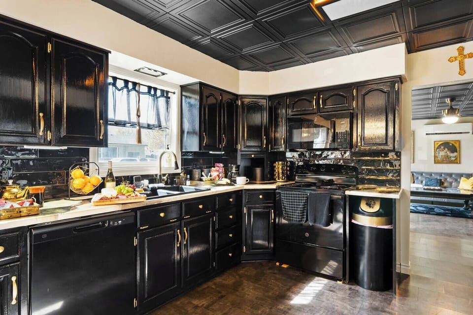 Elegant & Fully Equipped Kitchen 
Chic black cabinets, gold hardware, and a cozy open layout make this kitchen a dream for foodies, families, and wine lovers alike.