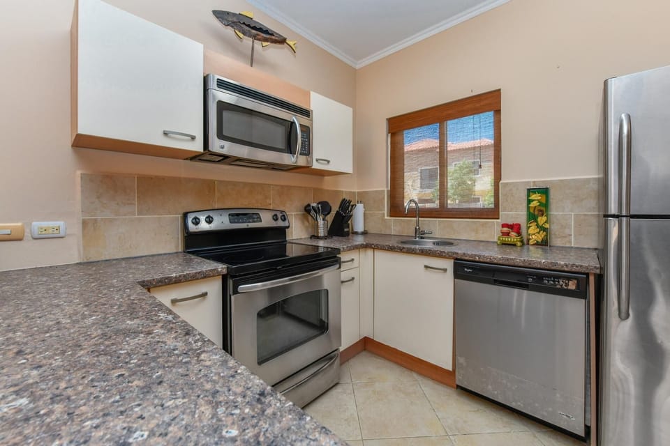 A large kitchen complete with all necessary appliances. There is a fridge, a stove, an oven, a microwave, a coffee maker, and more.