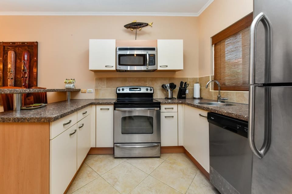 A large kitchen complete with all necessary appliances. There is a fridge, a stove, an oven, a microwave, a coffee maker, and more.