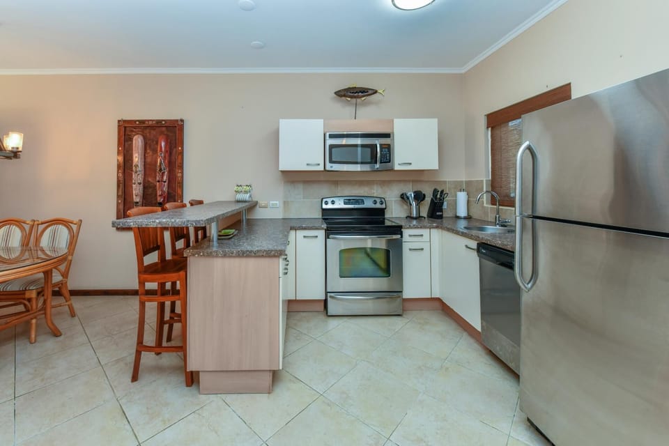 A large kitchen complete with all necessary appliances. There is a fridge, a stove, an oven, a microwave, a coffee maker, and more.