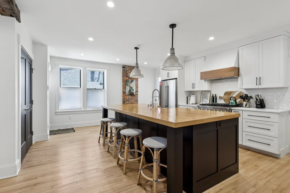 Stylish modern kitchen featuring a spacious wood-top island, professional range, and pendant lighting. Ideal for group meals, wine nights, and unforgettable gatherings in the heart of your stay.
