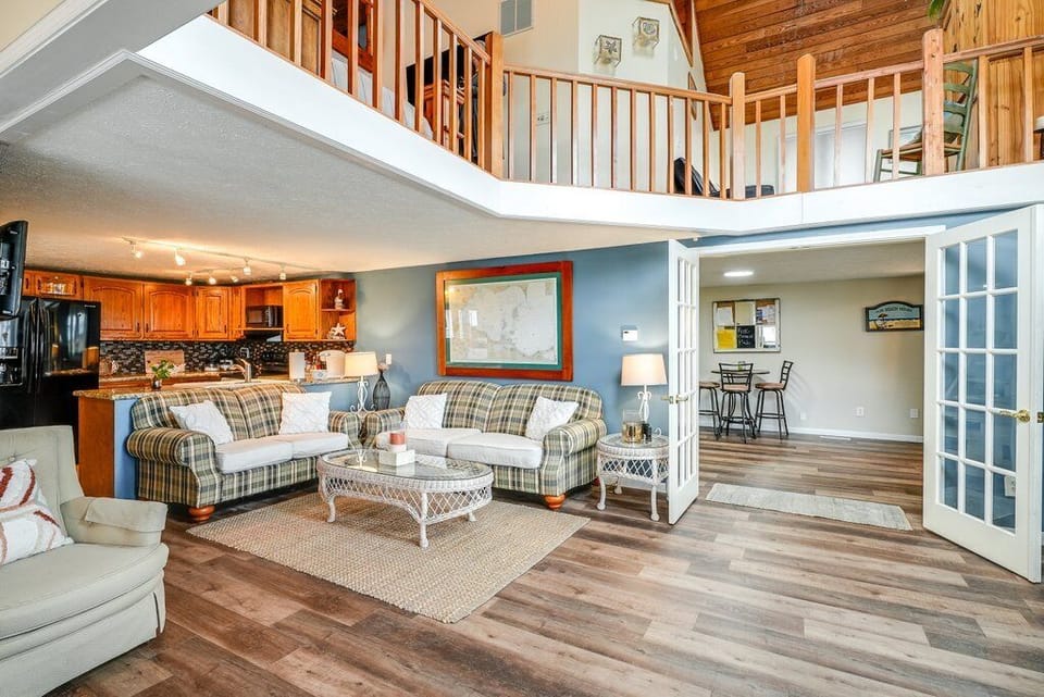 Living room with a glimpse of the gaming area and 2nd story balcony.
