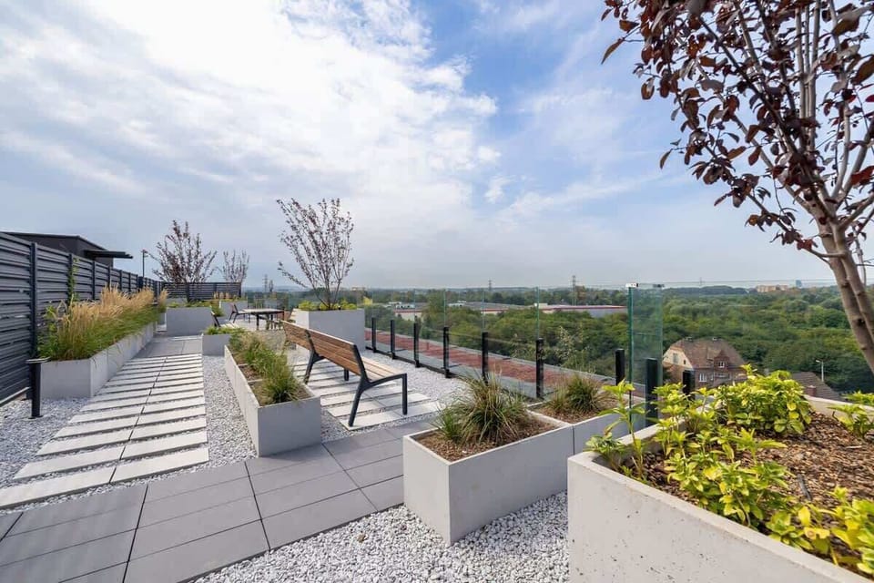 A spacious rooftop terrace with modern seating areas and a panoramic view of the city and greenery.
