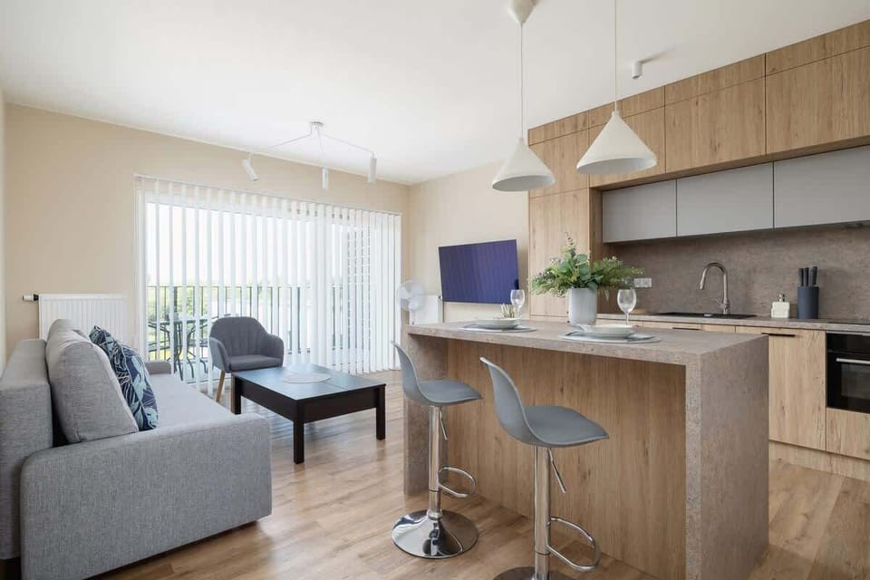 A dining area adjacent to the kitchen with a large window and natural wooden elements for a warm ambiance.
