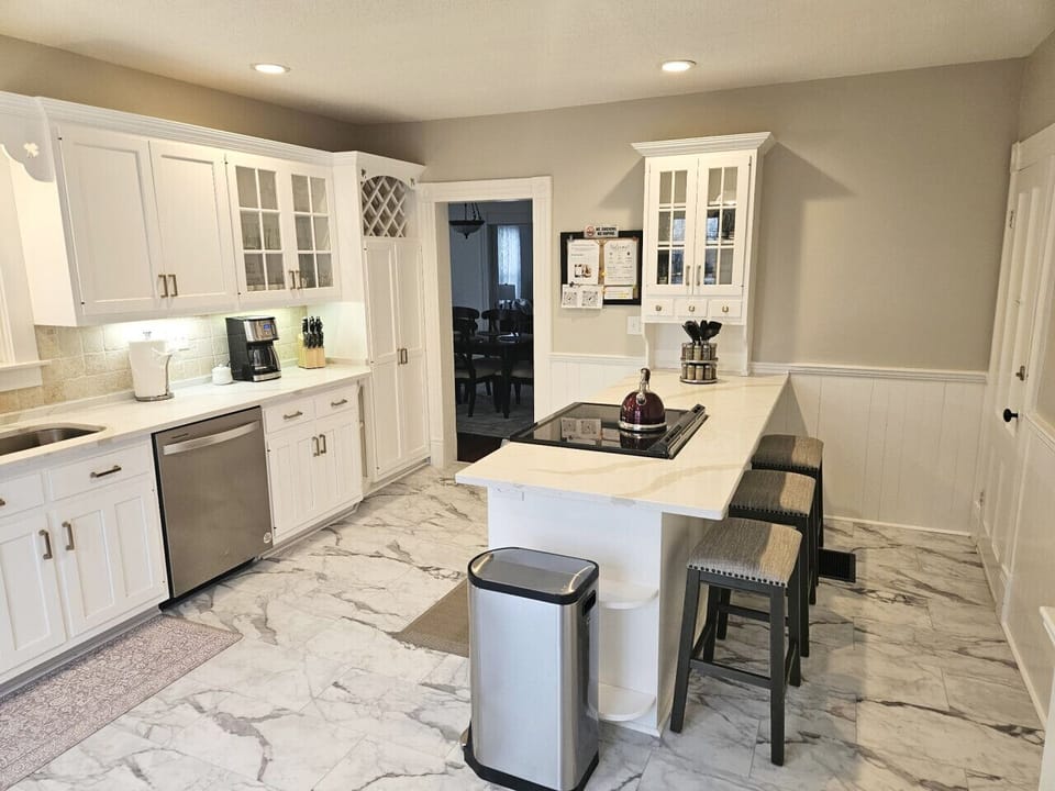 Bright, spacious kitchen featuring a large center island with seating for three—perfect for casual meals or morning coffee. Filled with natural light and modern finishes, it’s designed for both cooking and gathering.