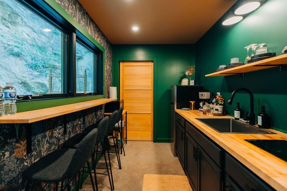 Share a simple cabin meal at the bar seating, with forest light pouring through the kitchen windows.
