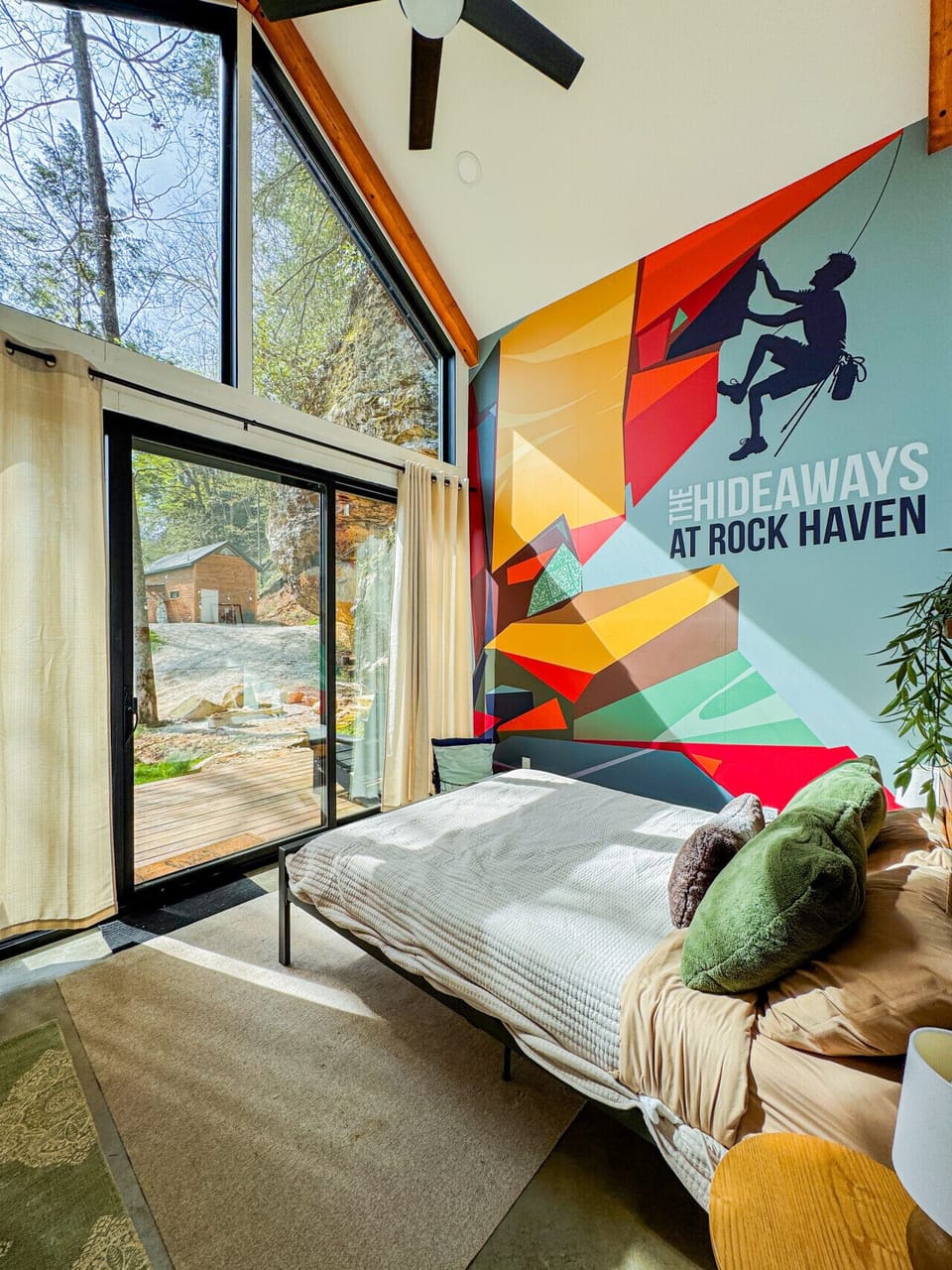 Bedroom with a sliding glass door straight out to the deck and a bold Hideaways mural. Wake up, step outside, and you`re already in the Gorge.