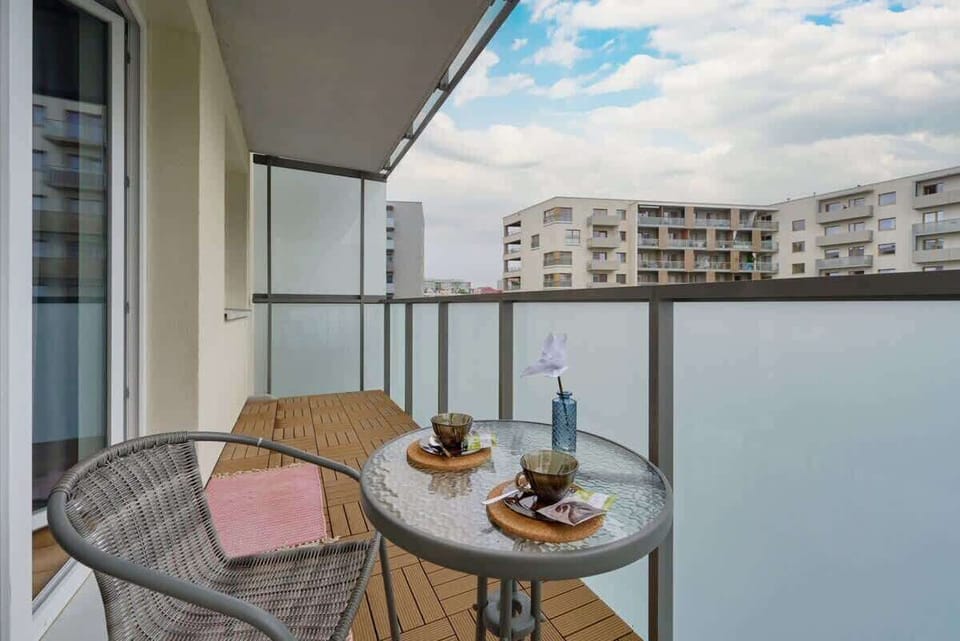 A balcony with a table and chairs, overlooking a cityscape, perfect for enjoying a meal outdoors.

