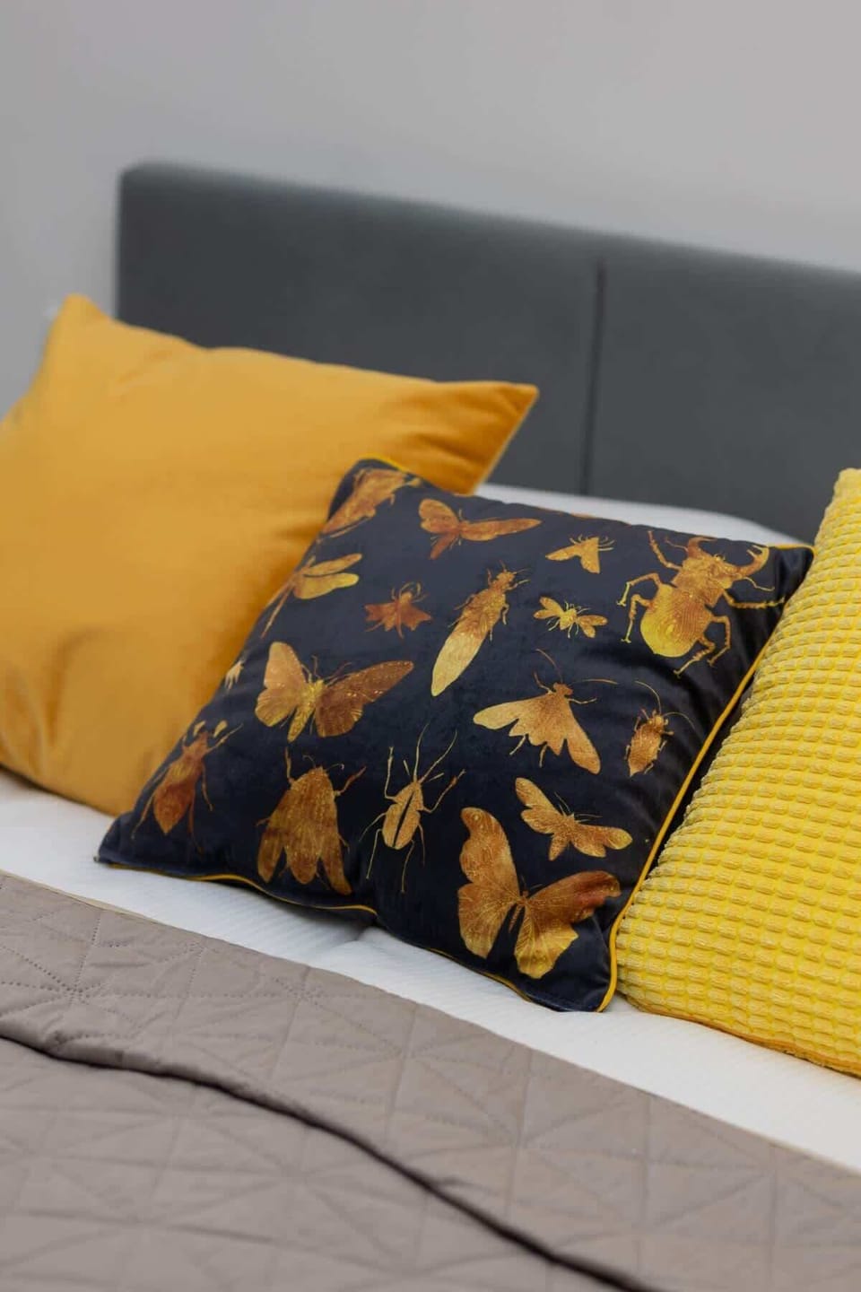 A close-up of the bed, showcasing decorative pillows in shades of yellow and black with a botanical pattern for a stylish touch.

