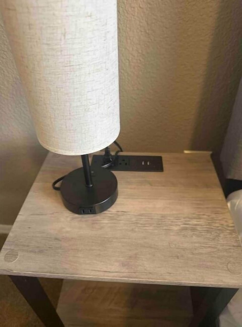 Nightstands with lamps and outlets to the left and the right of Queen bed.