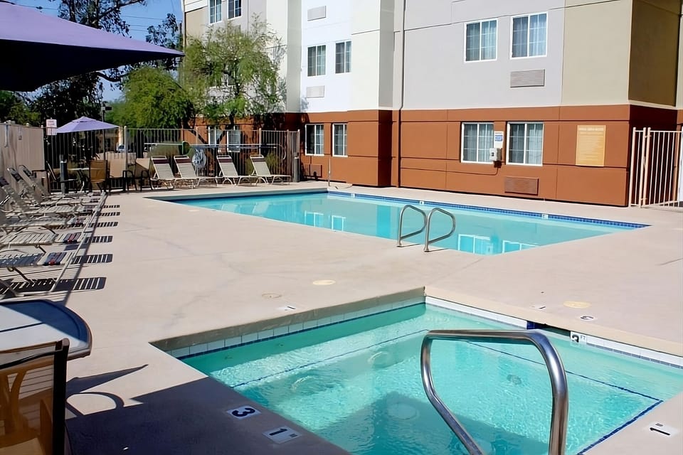Unwind poolside under umbrellas with sparkling, sunlit water.