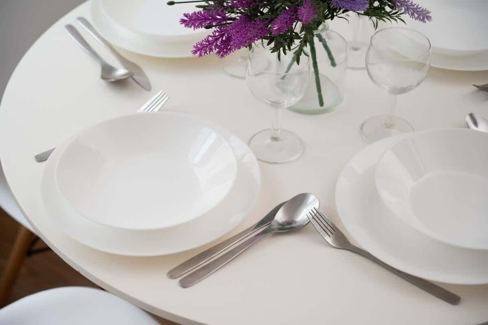 A detailed view of a table setting with neatly arranged plates, glasses, and a floral centerpiece, ideal for a small, intimate meal.

