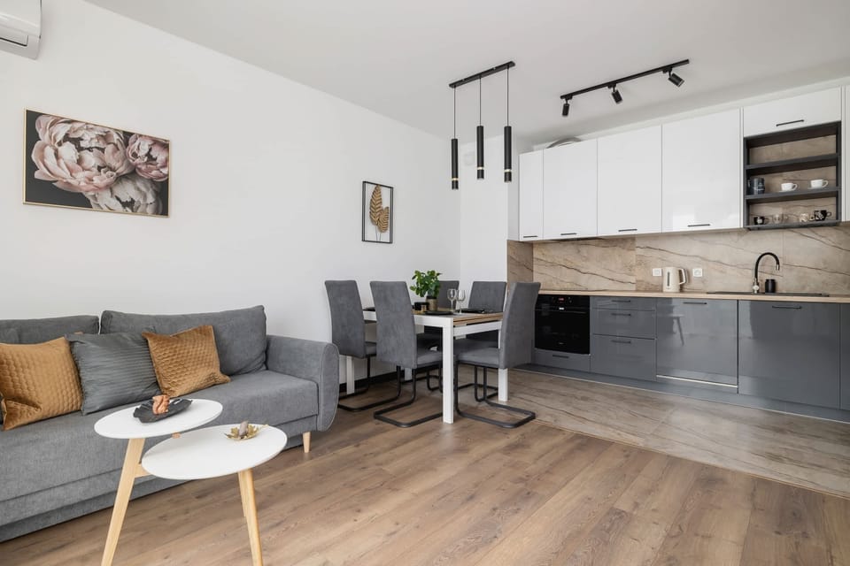 A cozy dining and living area with a gray sofa, white round coffee tables, and a simple decor style for a relaxed atmosphere.

