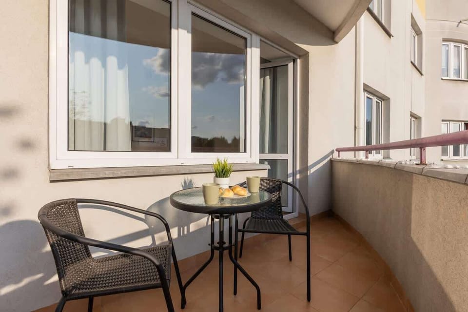 A small balcony with two wicker chairs and a round table, perfect for enjoying a morning coffee while overlooking the surrounding area.
