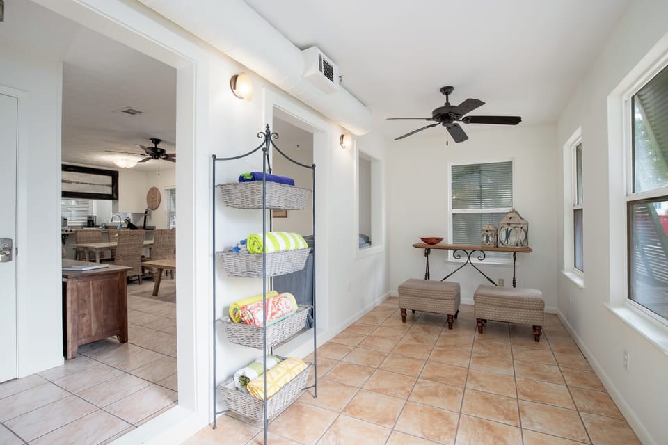Your bright sunroom offers a peaceful retreat with wicker seating and ceiling fan, perfect for morning coffee or afternoon relaxation.
