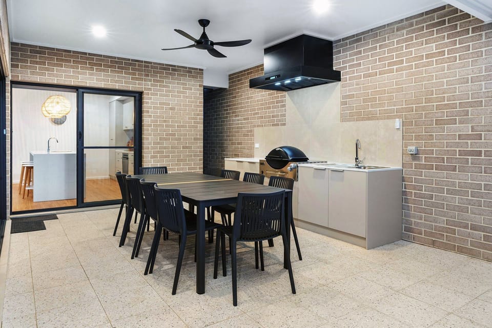 Kitchen leading to spacious undercover alfresco area with outdoor kitchen and Weber Q