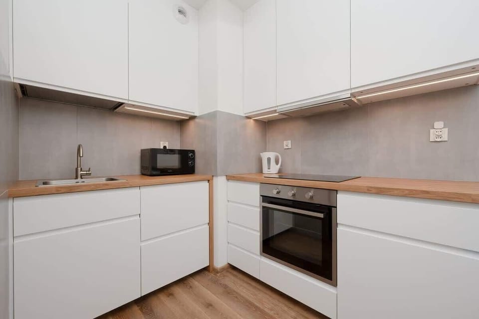 A kitchen with white cabinets, integrated appliances, and a wooden countertop, offering a sleek, modern design.

