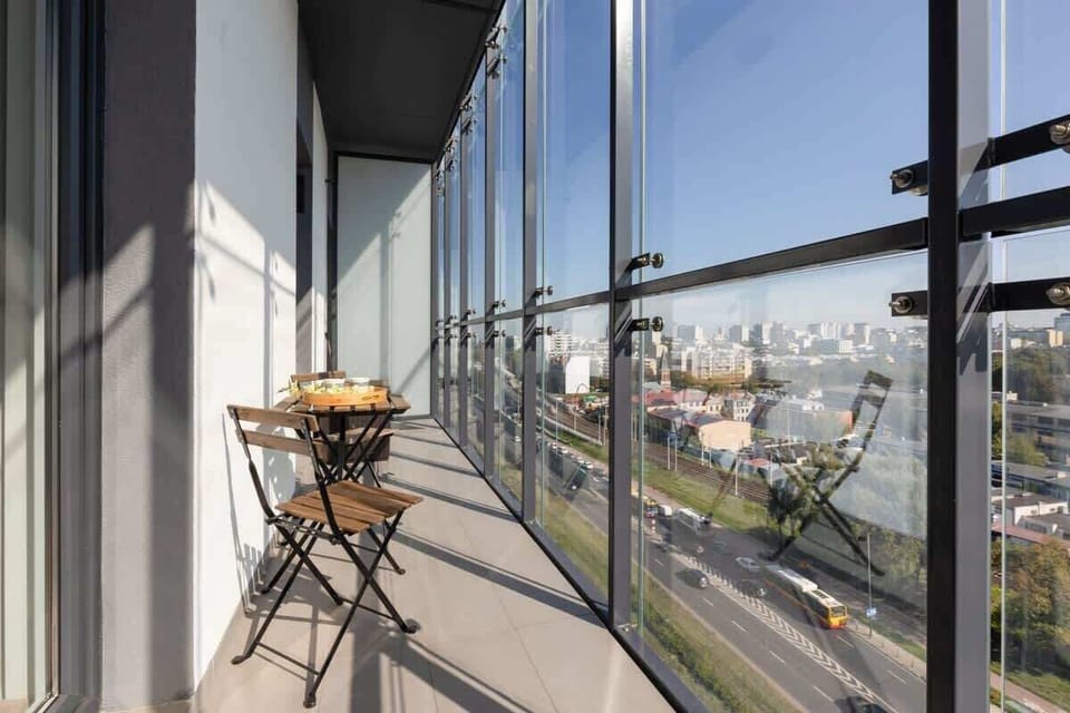A balcony with a small table and chair set, offering an outdoor retreat with views of the surrounding area.

